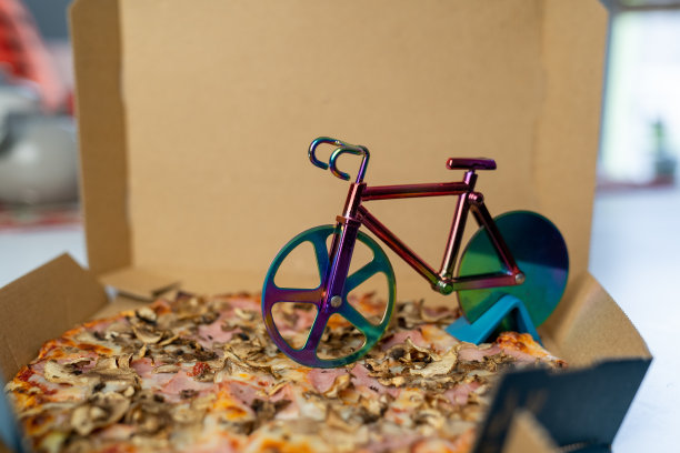 模糊效果，美味的披萨在纸盒桌上，自行车披萨刀在奶酪纸板，快餐外卖服务图片下载