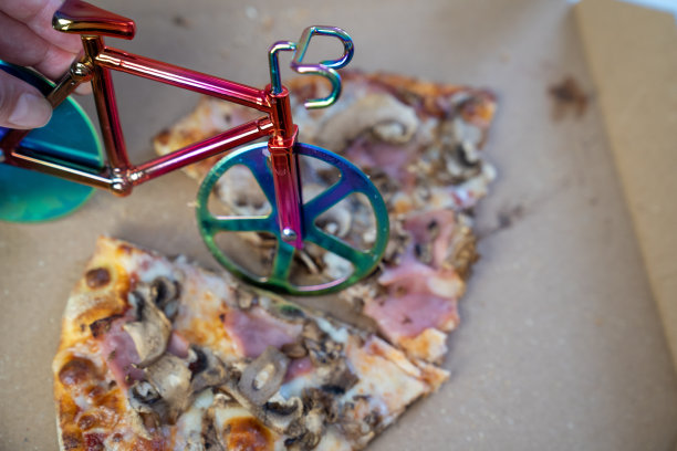 模糊效果，女人用手在桌子上的纸箱里切美味的披萨，自行车切披萨刀在纸板上切奶酪，快餐外卖服务图片下载