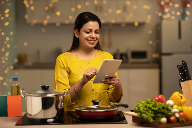 印度妇女在厨房做饭时享受的肖像。库存图片图片下载