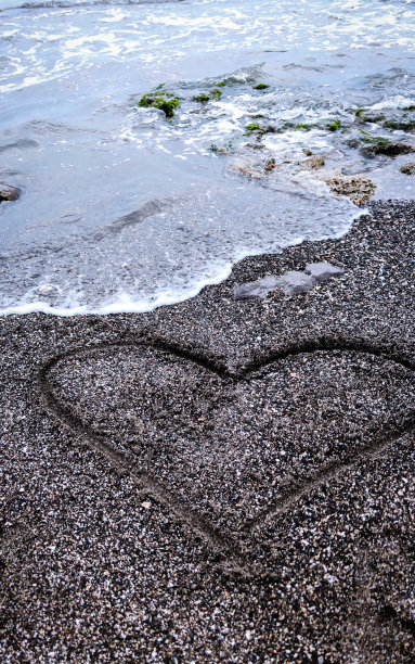 爱的象征写在黄昏的黑色沙滩上。图片下载