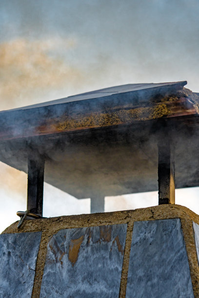 在一个乡村小镇，日落时分，烟从一个村庄房子的烟囱里冒出来的细节。图片下载