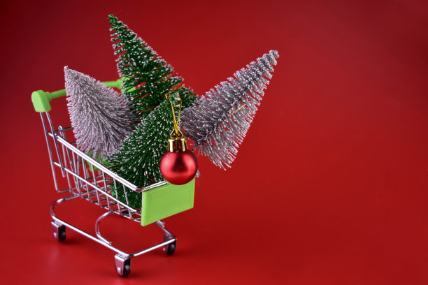 圣诞树在超市手推车上的红色背景。圣诞购物。图片下载