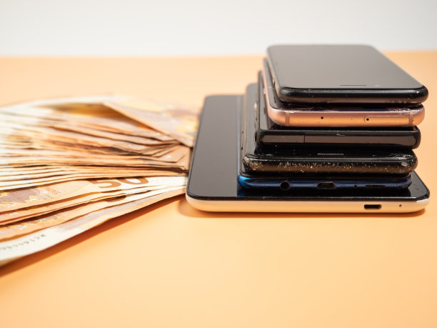 很多旧智能手机和橙色背景上的钱。旧手机和欧元钞票。图片下载