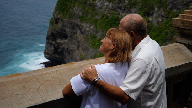 退休者退休后的生活。一对老夫妇在异国他乡度假，在观景台上拥抱着大海。男人向女人展示大自然的伟大。图片下载