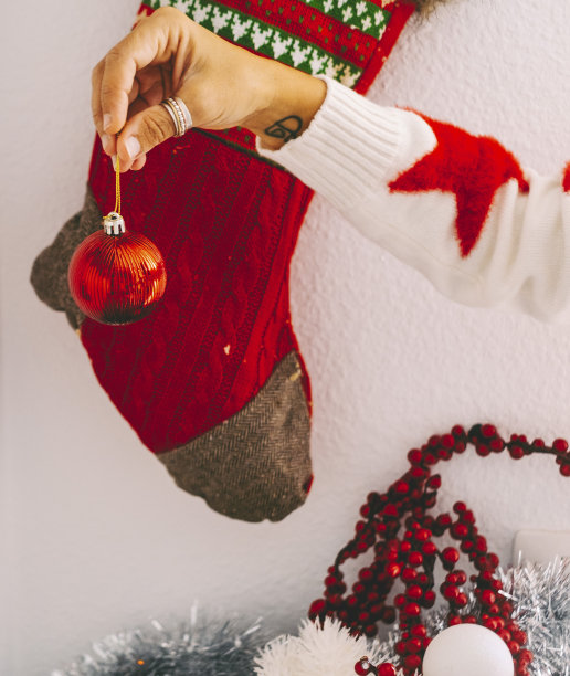 圣诞假期和家居装饰概念形象。女人手握圣诞球与袜子在背景。红色十二月的颜色概念。家庭墙壁装饰和树木图片下载