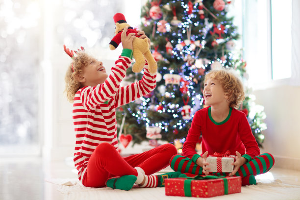 孩子在圣诞树旁。圣诞节孩子们在壁炉边图片下载