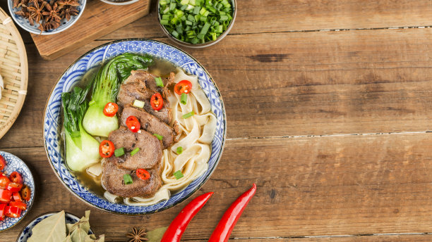 麻辣红汤牛肉面放在木桌上的碗里图片下载