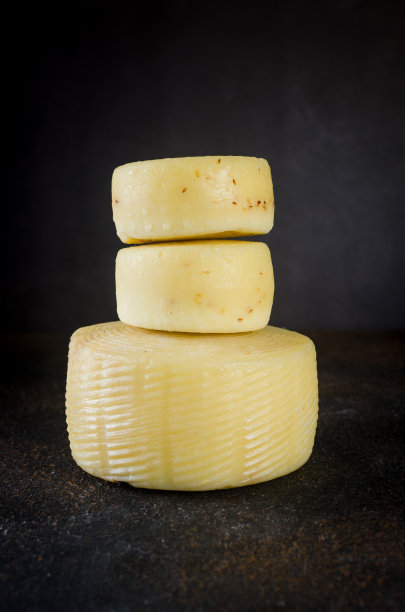 不同种类的奶酪头堆在黑暗的桌子上图片下载