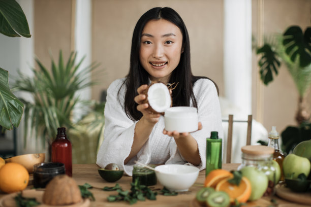 专注于椰子和玻璃罐，年轻的亚洲妇女拿着一半的椰子和自制奶油图片下载