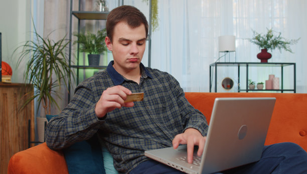 年轻的少年男子使用信用卡和笔记本电脑，转账，网上购物图片下载