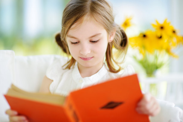 可爱的小女孩在夏天的白色客厅里看书图片下载