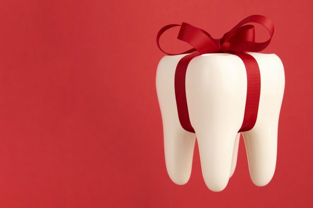 白色牙齿模型与蝴蝶结丝带在红色背景与复制空间图片下载