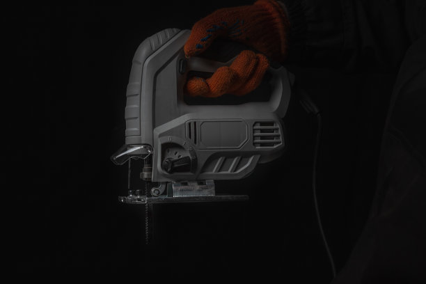 电动拼图，在妈妈的手锯木材隔离在黑色背景图片下载