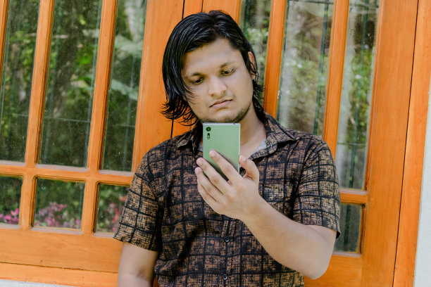 一个英俊的年轻人看着他的手机屏幕图片下载
