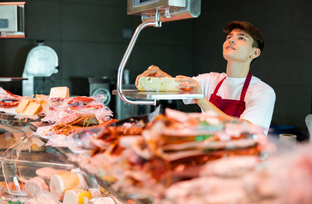 年轻的推销员在杂货店称奶酪的重量图片下载