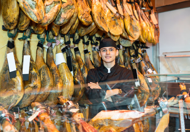 屠夫肖像的背景上的机架与悬挂各种jamon图片下载