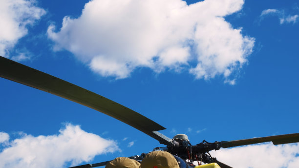 从下方从侧面蓝色直升机机身和铰接主旋翼拍摄。深蓝色直升机机身，圆形窗户和主螺旋桨。镜头向上移动，显示直升机的机身和旋翼图片下载