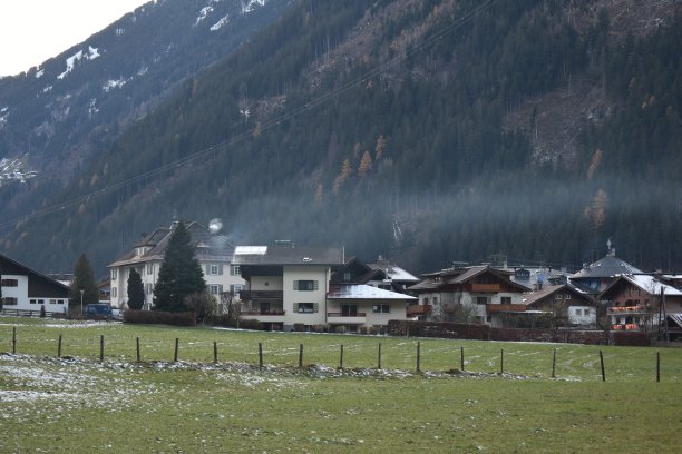 寒冷的冬夜，奥地利阿尔卑斯村庄的烟囱里冒出的烟雾图片下载