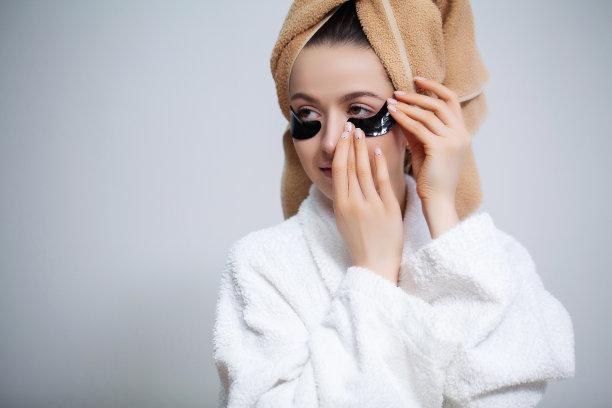 身穿白大褂的美女在眼睛上敷眼罩进行皮肤护理图片下载