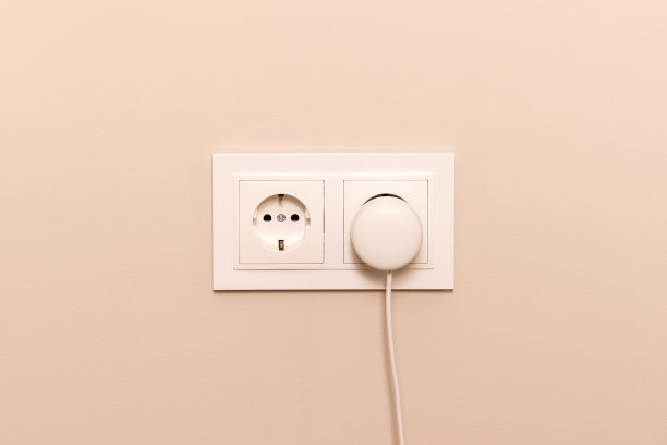 米黄色墙上带插头的电源插座图片下载