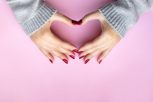 女人的手，品红色，酒红色的指甲做心形符号图片下载