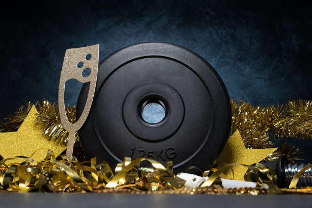 健身跨年作文。健身房哑铃杠铃重量盘和金色装饰品。新年锻炼计划。图片下载