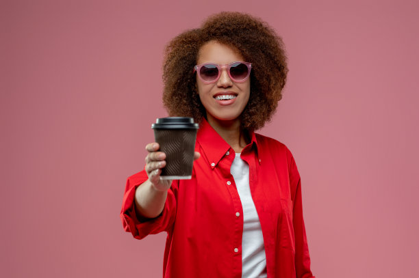 穿着红夹克的卷发美女正在喝咖啡图片下载