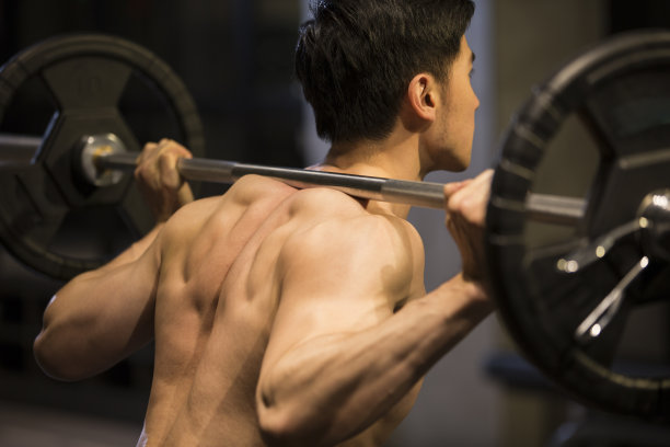 年轻男子举杠铃进行重量训练图片下载