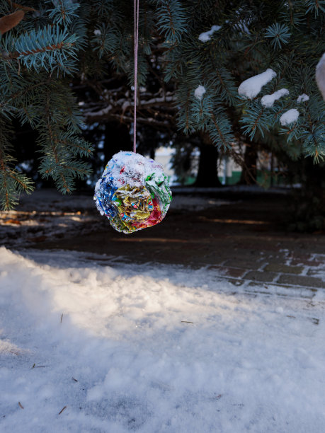 自制的新年玩具放在圣诞树上，上面盖满了雪。图片下载