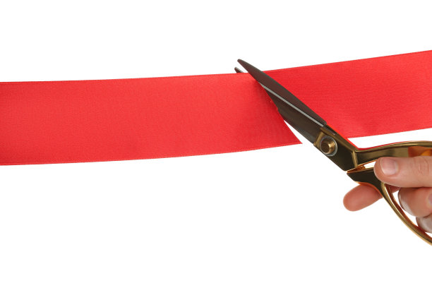 男子在白底上剪红丝带，特写图片下载