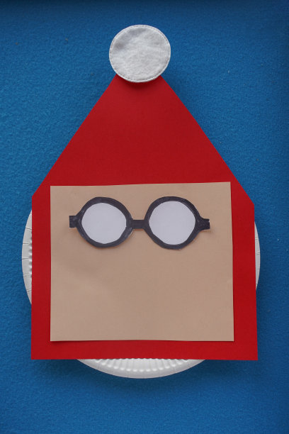 圣诞圣诞贺卡手工制作。一步一步的照片指导。DIY的概念。用黑白纸剪出圣诞老人的眼镜，粘在脸上。步骤7 - 14。俯视图，平面布局图片下载