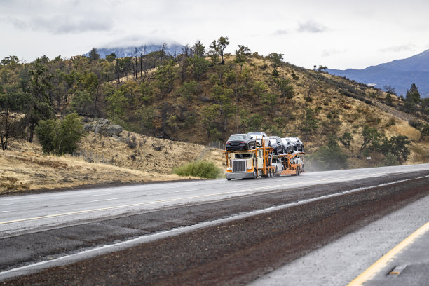 米色和橙色的大钻机汽车拖车半卡车运输汽车的两级模块化半挂车运行在高速公路上，在加利福尼亚州图片下载