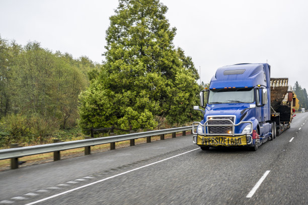 重型大卡车蓝色半挂车牵引车运输超大货物的阶梯半挂车在宽阔的公路上运行图片下载