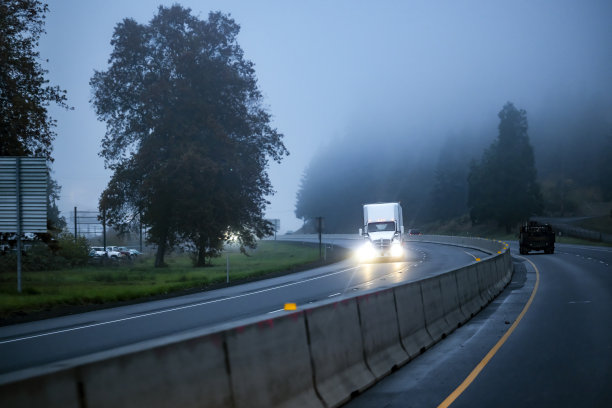开着大灯的白色半挂车在大雾弥漫的早晨行驶图片下载