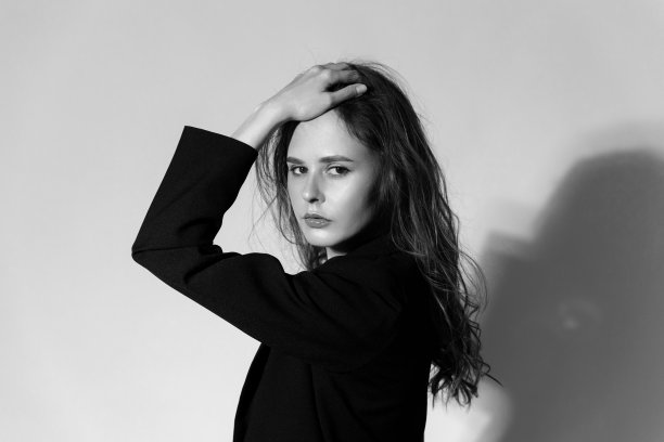 服装设计和广告概念。白人女孩，深色长发，黑色夹克，灰色背景，特写脸。黑白照片图片下载