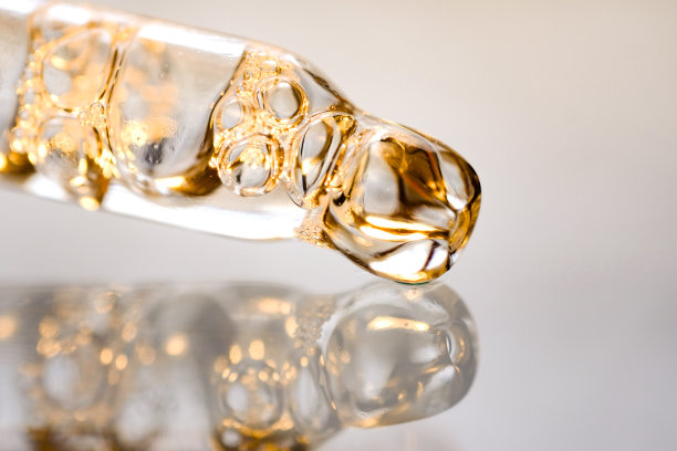 浅色背景上带气泡的金色精华液移液管。微距摄影，侧视图，文字空间。图片下载