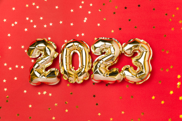 2023年新年气球庆祝卡。金箔氦气球编号2023和金色五彩纸屑星星孤立在红色背景。平铺，圣诞快乐，节日快乐。图片下载