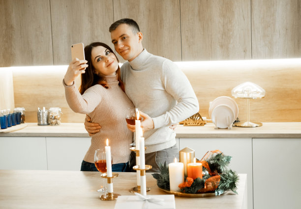 年轻幸福的情侣庆祝圣诞节，捧着酒杯，拥抱，自拍图片下载