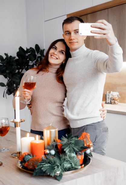 年轻幸福的情侣庆祝圣诞节，捧着酒杯，拥抱，自拍图片下载