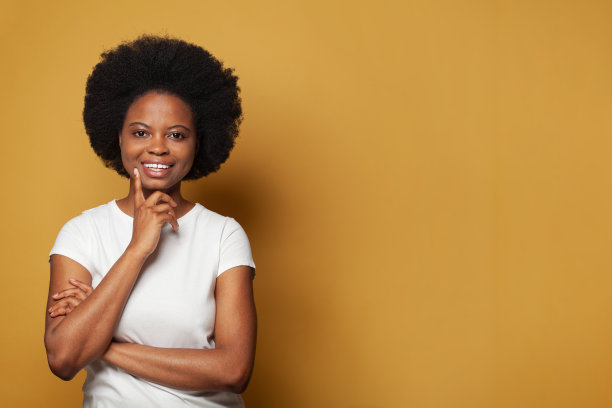 漂亮的年轻女子在白色t恤上思考鲜艳的黄色背景图片下载