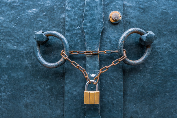 近距离看上锁的铁门和挂着的黄金色锁图片下载