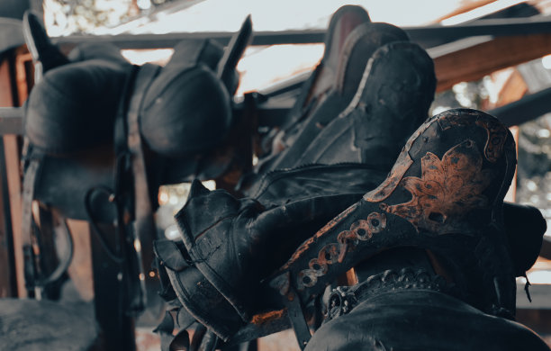 马场的木栅栏上挂着皮革马鞍图片下载