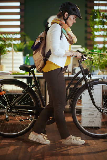 时髦的商业妇女在自行车头盔在现代生态办公室图片下载