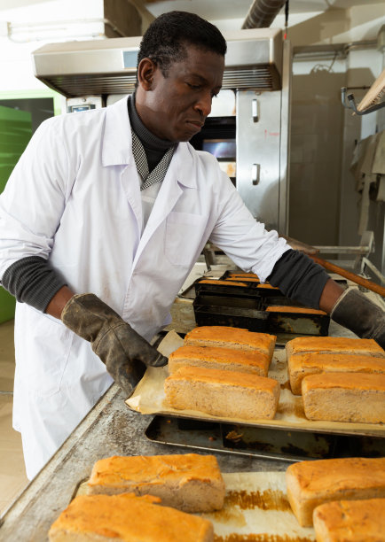 非洲面包师从烘焙模具中取出面包图片下载