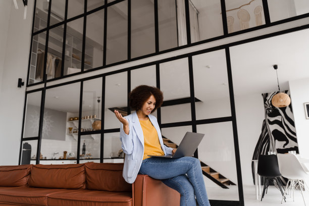 在项目成功后，与朋友和同事进行视频会议，并在线远程娱乐。非裔美国女孩与笔记本电脑微笑，笑着与同事讨论一些事情。图片下载