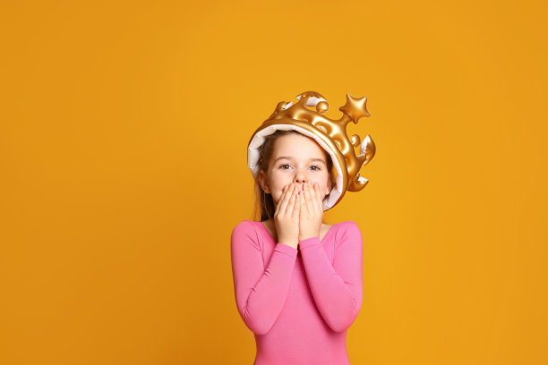 可爱的女孩在充气皇冠上的黄色背景。小公主图片下载