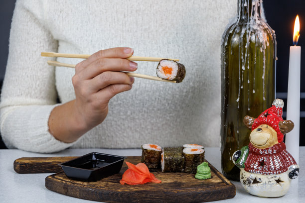 日本红鱼卷，装在敞开的纸板箱里。女孩用筷子吃寿司。表装饰图片下载