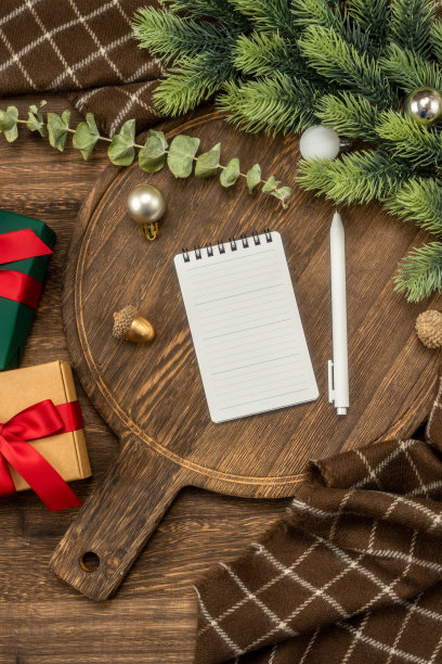 笔记本和笔在木制砧板与圣诞装饰。圣诞节待办事项清单或愿望清单。图片下载
