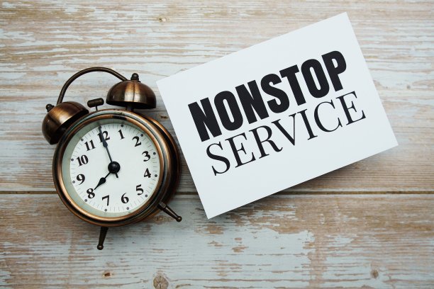 不间断的服务文本和闹钟在木制背景图片下载