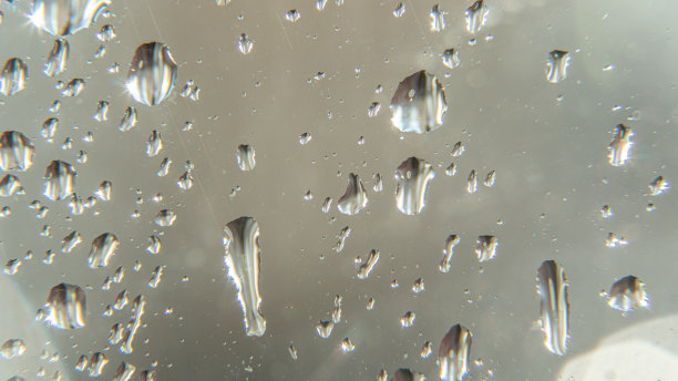 雨滴落在窗户上。下雨，阴雨绵绵，令人沮丧、沉闷的天气。湿漉漉的水滴。大水珠飞溅在玻璃上。窗户上有水滴和水花。图片下载